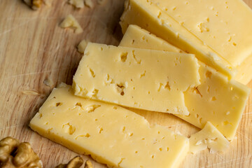 Sliced hard cheese with holes and walnuts