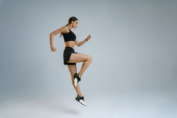 Fototapeta na wymiar Athletic active woman jumping on studio background . Dynamic movement