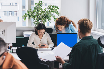 Group of colleagues sitting at table working on business project at workplace