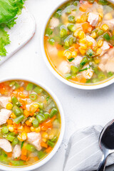 Light vegetable soup with chicken, corn and green beans. Comfort food. White table background, top view