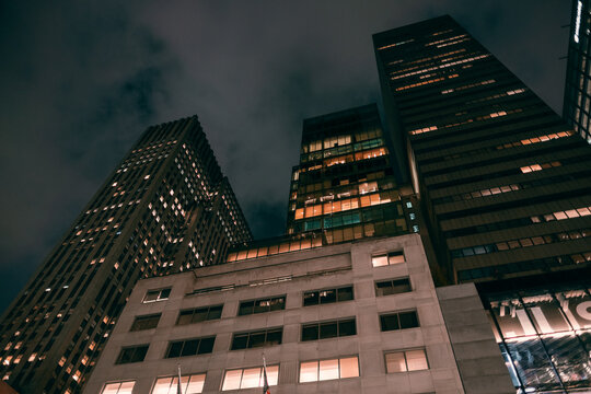 Old city building office at night. Low angle view of skyscrapers. Looking up perspective. Bottom view of modern skyscrapers in a business district. Cityscape at night.	
