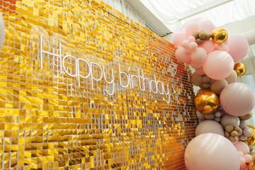 A large festive photo zone for a birthday, decorated with gold sequins, pink, gray and gold balloons of different sizes. Celebrating concept