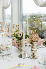 Decorative arrangement of candles and a vase with white and pink flowers to decorate the wedding table. Celebrating concept