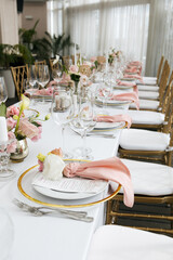 Wedding decorations. Served wedding table with decorative fresh pink flowers and candles. Celebration details. Flower composition roses plates and candles in candlesticks