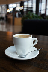 Close up white cup of coffee latte on wood table in cafe
