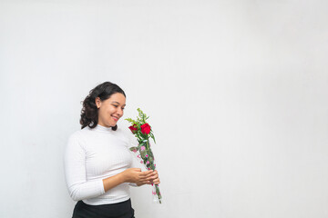 Hermosa joven mujer sonrie feliz mientras sostiene ramo de rosas