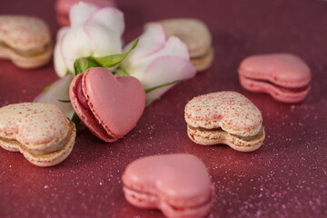 Heart-shaped macarons with roses on glittery pink background, Valentines day