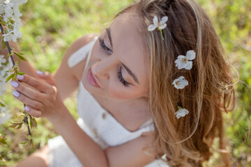 Naklejka premium the portrait of beautiful woman walks in the blooming garden. The girl dressed white sundress