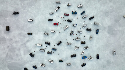 Colorful cars stand on transparent blue ice ice there are many people involved in ice fishing