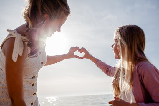 Mither holds the doughter hand and walks in the baech together against the background the sea or coean