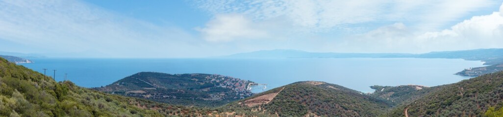 Fototapeta na wymiar Summer Aegean sea coast top view. The Pyrgadikia village on shore (Sithonia, Halkidiki, Greece). Athos mount silhouette leftward in far.