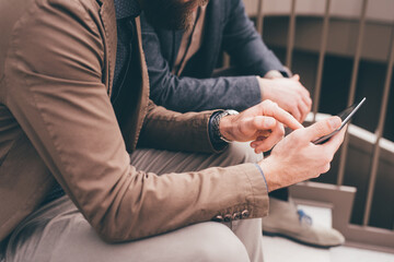 Unrecognizable two businessman sitting staircase using tablet computer