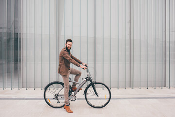 Fototapeta na wymiar Contemporary bearded young stylish businessman going to work by bike commuting the carbon-free way