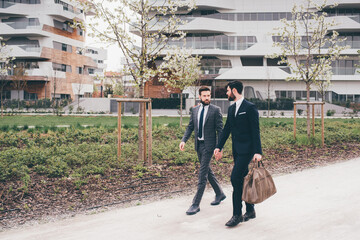 Two young elegant businessmen walking outdoors together in the streets