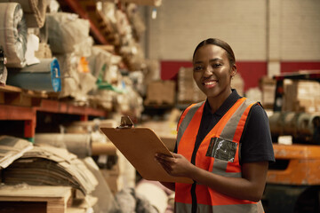 Smiling young African female warehouse worker doing inventory