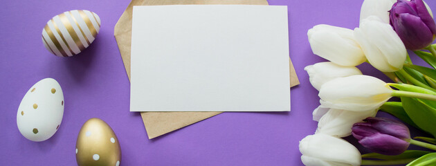 Banner with Easter greetings: paper letter copy space on a purple background. Bouquet of white tulips and easter eggs golden and with pattern