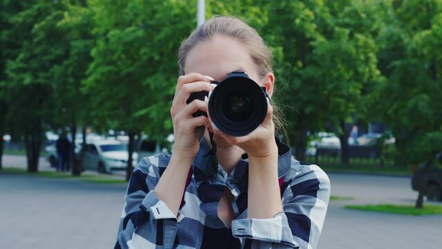 Positive girl takes pictures of sightseeing attractions while travelling in strange city or country. Young woman smiling, shooting urban landmarks. Front view. Wedding female photographer