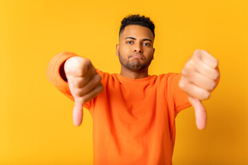 Unhappy young Indian man showing rejection and negative with thumbs down gesture isolated on...