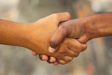 Two human hands are joined together and the background is blurred