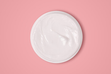 White cream in a jar on a pink background. View from above