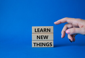 Learn new things symbol. Concept words Learn new things on wooden blocks. Beautiful blue background. Businessman hand. Business and Learn new things concept. Copy space.
