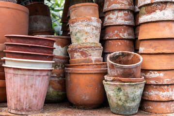 Fototapeta premium Clay pots. Stacks of old pots. ceramic dishes for flowers. Flower stock. Used items for recycling or reuse. Preparing garden tools.