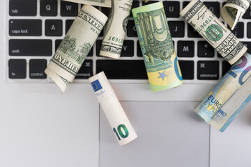 Make money online or online income concept. Roll of Dollar banknotes on laptop computer.