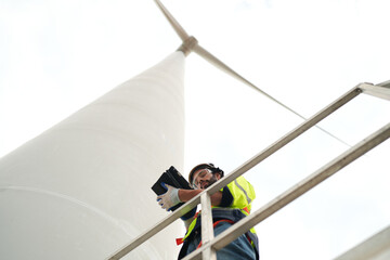 Wide perspective of wind turbine engineers walking with coworker in wind farms © FotoArtist