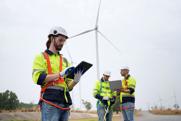 Wide perspective of wind turbine engineers walking with coworker in wind farms © FotoArtist