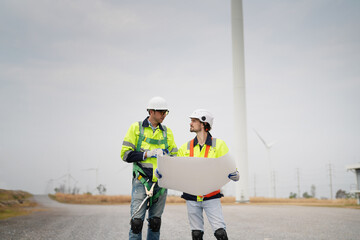 Wide perspective of wind turbine engineers walking with coworker in wind farms