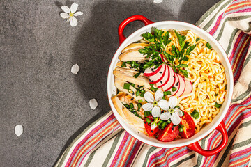 Asian noodles with chicken, vegetables, and herbs in a red bowl. Traditional Japanese soup