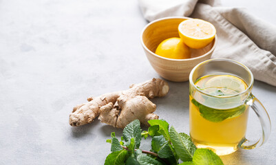 Aroma glass of tea with fresh lemon, mint and ginger on a light background with morning light. The...