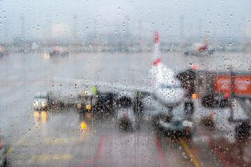 Blick auf ein Flugzeug durch eine mit Regentropfen bedeckte Glasscheibe 