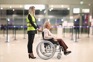 Female assitance worker at the airport with an older woman in a wheelchair