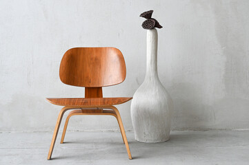 Wooden chair and big white vase over concrete wall. Cozy interior accessories