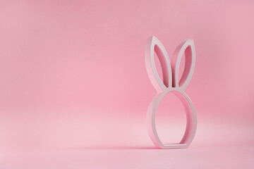 Wooden easter bunny figurine on the pink background, easter minimal concept with copy space