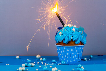 Birthday cupcake with a burning candle, blue background, homemade cakes, ball decorations