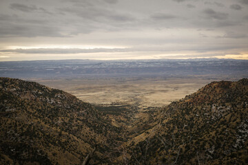 Obraz premium Wide view of mountain valley in Grand Junction Colorado overlooked flat desert and snow covered mesas