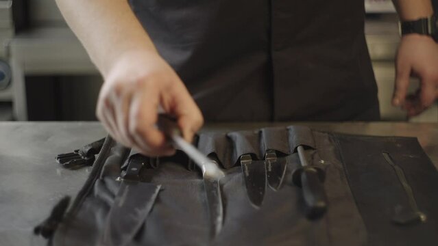 Close-up of professional kitchen knives being taken by the chef. The chef chooses a knife for cutting vegetables.