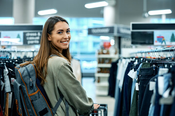 Happy woman enjoys in shopping at clothing department and looking at camera.