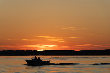 Silhouette of two fisherman on the boat. Beautiful sunset on the background.