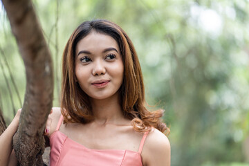 Young woman in pink dress enjoying the tranquil scenery with bokeh park background