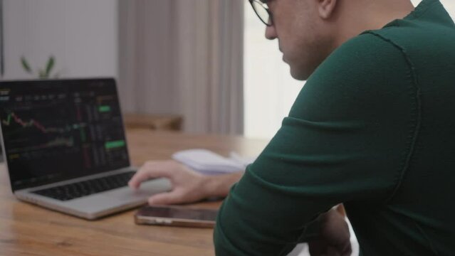 online trader checking crypto currency graphs on laptop app screen, analist working at home with stock exchange market online