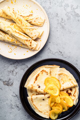Plate of fresh crepes with orange on gray background, crepes Suzette