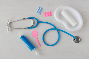 Medical children's instruments on a light table. Doctor's first aid kit. Syringes, pills, stethoscope - game set for training future doctors.

