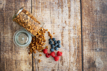 granola with raspberries and blueberries on a wooden background