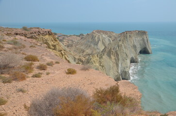 nice view to the Persian Gulf from a hill with some dry plants to the rock formation of Hormuz island, Iran