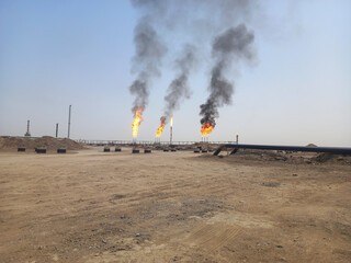 Crude Oil pipelines with burning flames in distance.