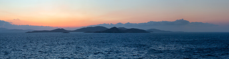 Rocky Island on Mediterranean Sea. Rinia near Mikonos, Greece, Europe. Nature Background Panorama. Sunrise Sky