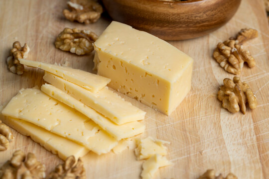 Sliced hard cheese with holes and walnuts